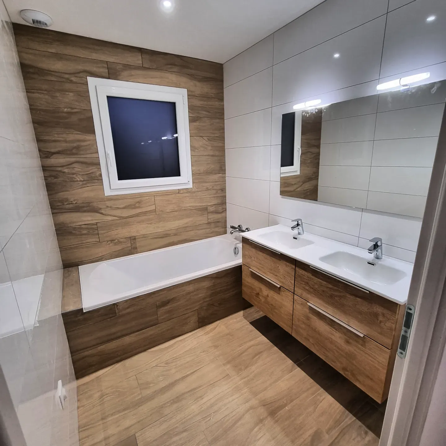 Salle de bain carrelée par Dôme Carrelage : sol et mur en carrelage imitation bois, faïence blanche grand format